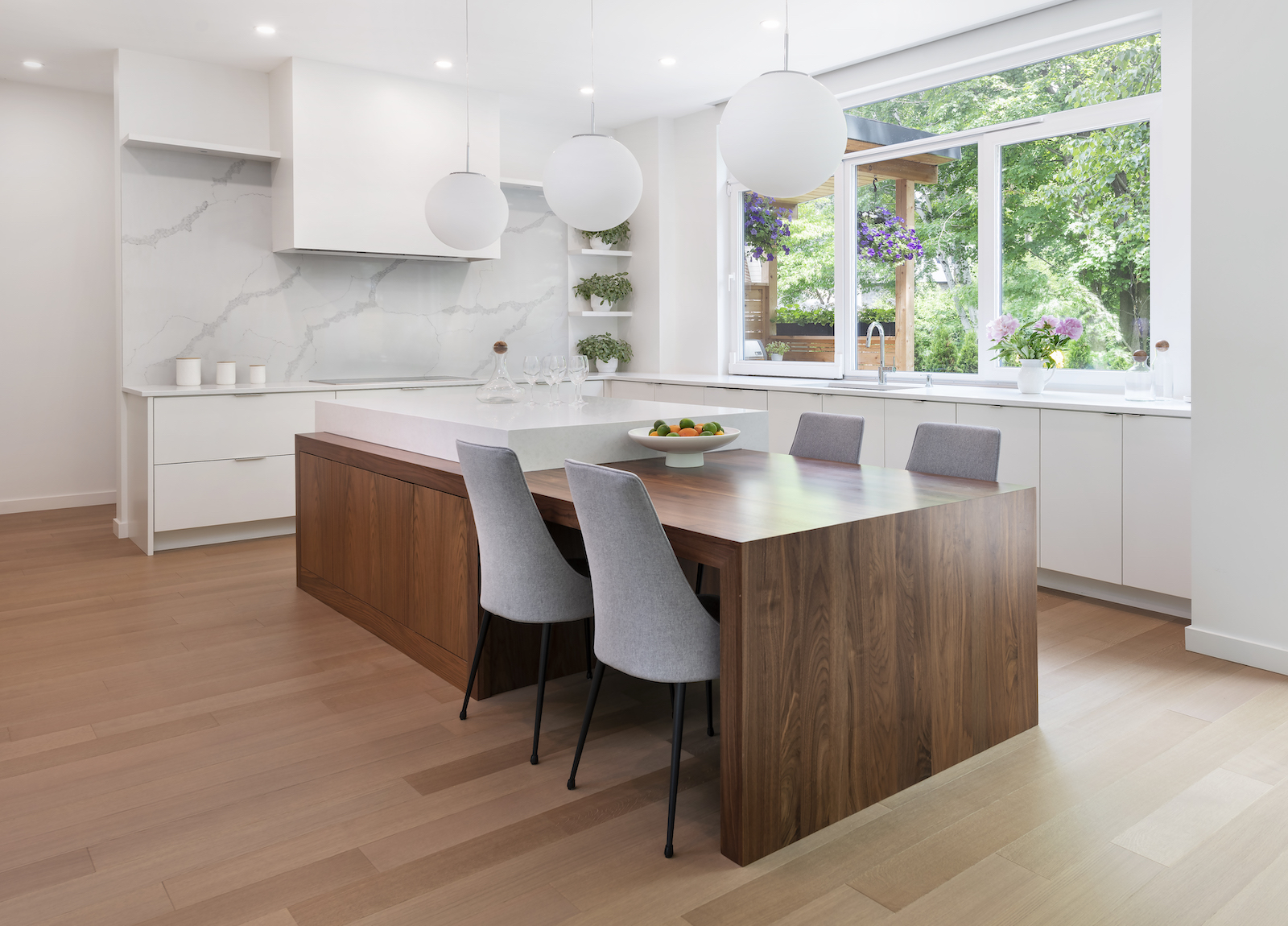 Modern Scandinavian kitchen featuring a natural walnut island, white cabinetry, white veined quartz backsplash and white oak flooring.